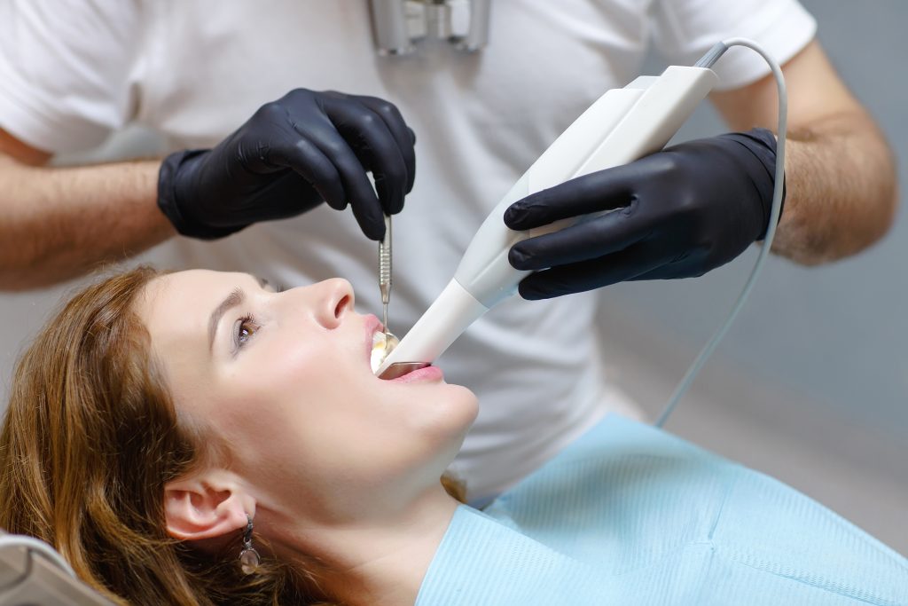 The dentist scans the patient's teeth with a 3d scanner.